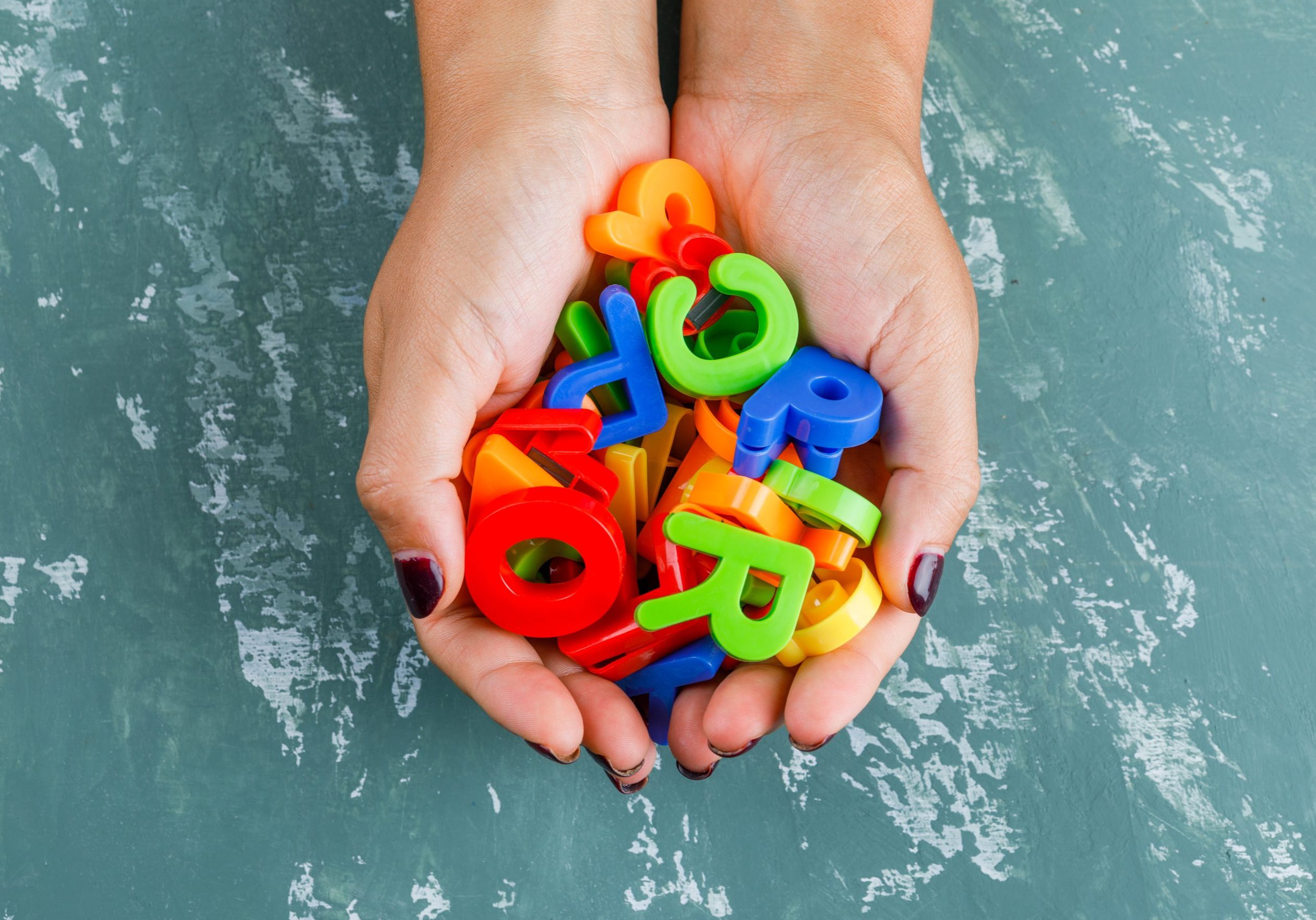 Back to school concept on plaster background flat lay. woman holding colorful letters.